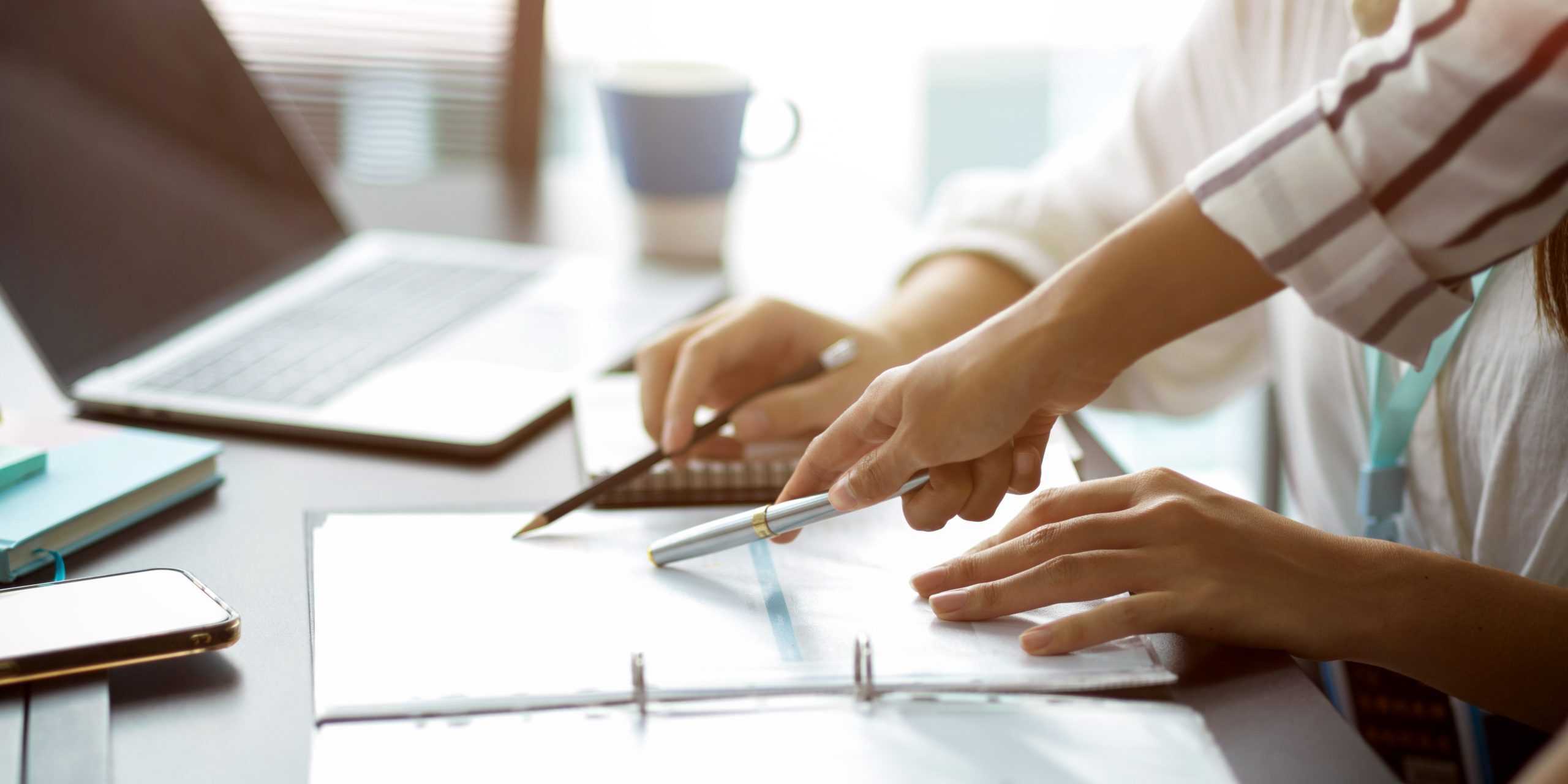 Cropped image of Two businesswomen discuss and voting business strategy plan for the next project. pen pointing on papers