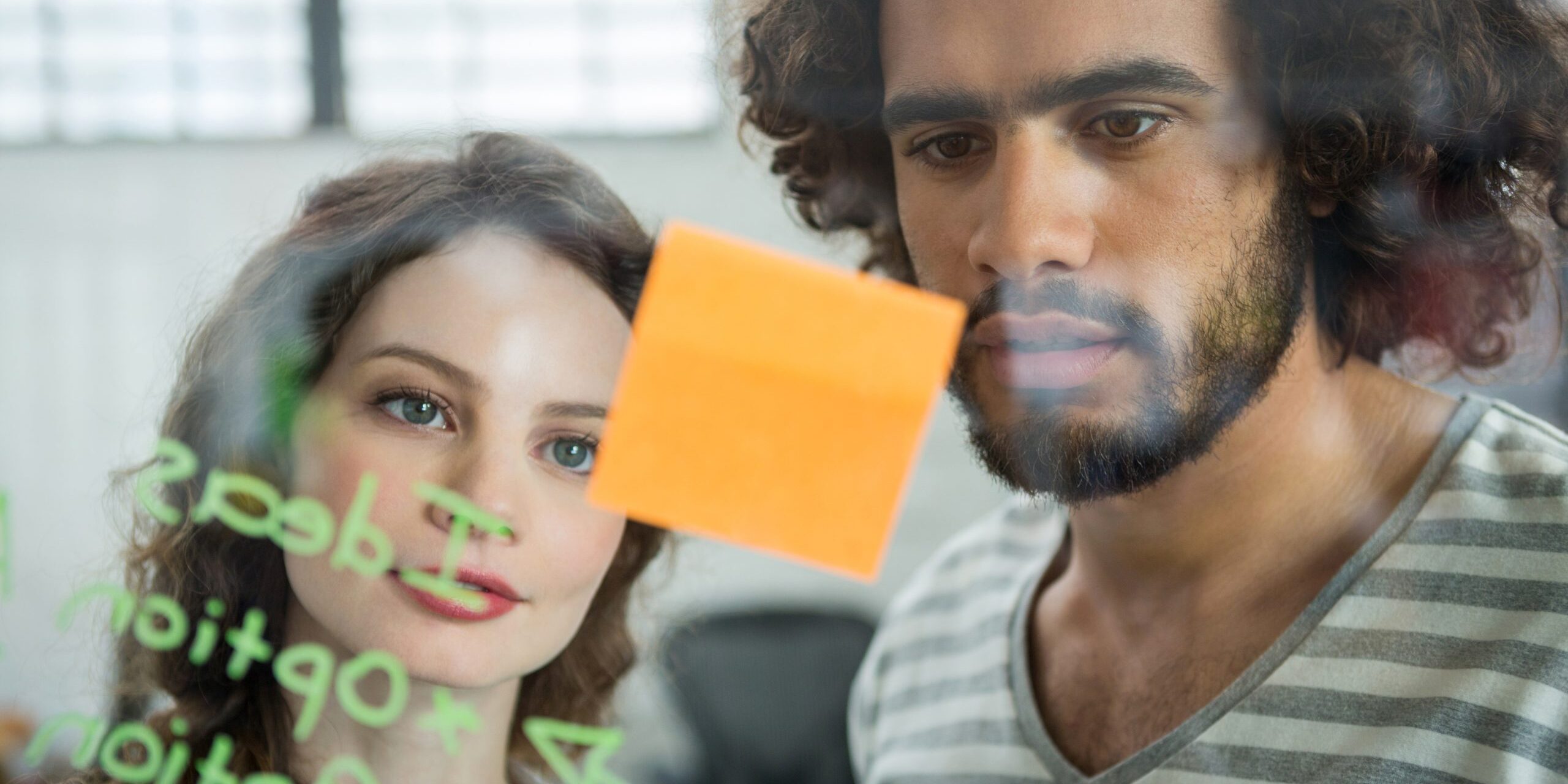 Executives looking at sticky note in creative office